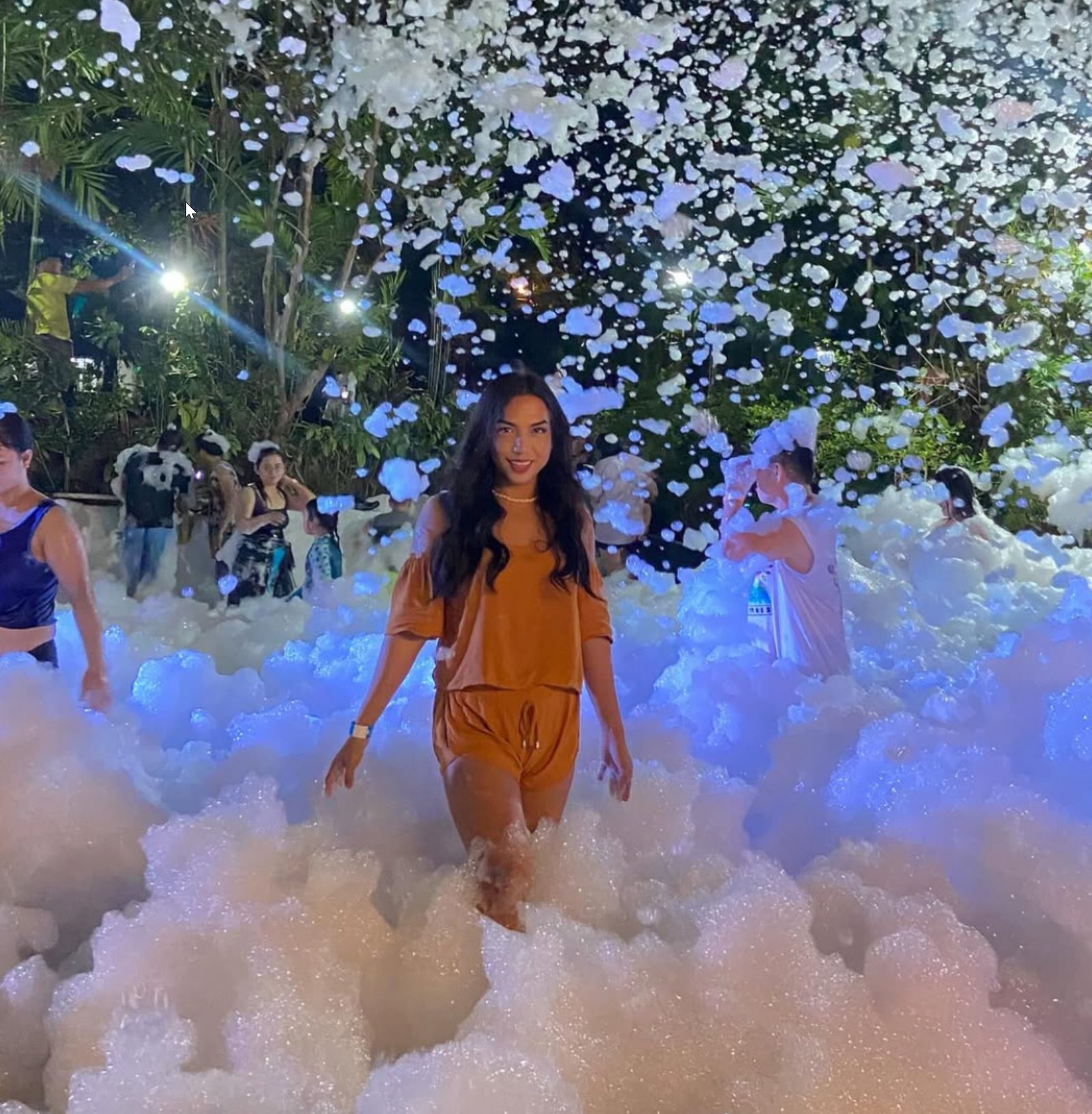 Woman standing in foam under blue lighting at a night event