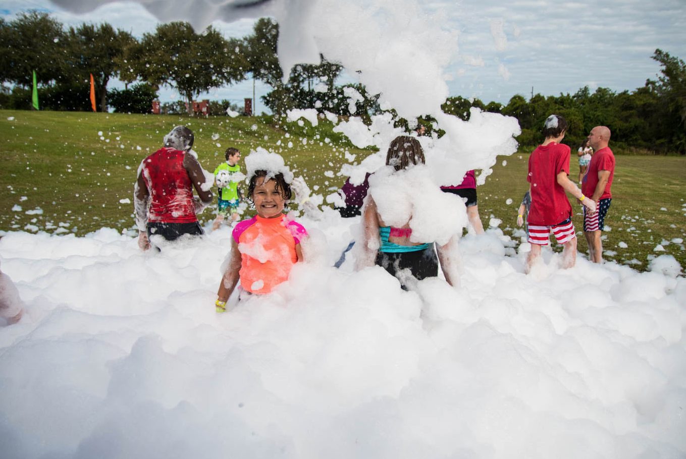 Families playing in deep foam at a park during the day